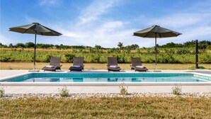Piscina com quatro espreguiçadeiras e dois guarda-sóis.