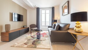 Un salon moderne avec un canapé, une table basse, un téléviseur et une lampe.