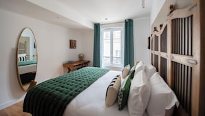 Un dormitorio con cama, un espejo grande, un aparador de madera y una ventana con cortinas.