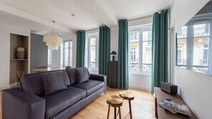 Una sala de estar moderna con un sofá gris oscuro, una mesa de centro de madera y una lámpara de araña.