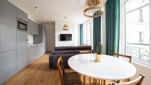 Una cocina moderna con gabinetes grises, un horno empotrado y un televisor de pantalla plana.