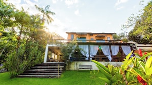 A building with a staircase leading to a covered area, surrounded by lush greenery. - VOA Pousada Recanto dos Colibris (Paraty)