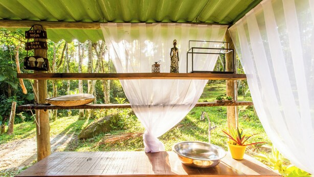 A rustic wooden table with a white cloth, a metal bowl, and a potted plant. - VOA Pousada Recanto dos Colibris (Paraty)