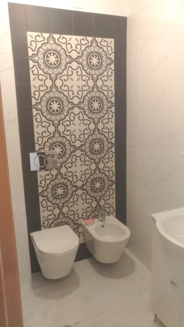 A bathroom with two toilets, a bidet, and a sink.