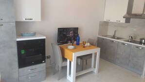 A compact kitchen with a dining area, a built-in oven, and a TV on the wall.