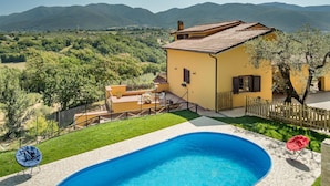 Une propriété résidentielle dotée d’une piscine, d’un jardin clôturé et offrant une vue sur les montagnes.