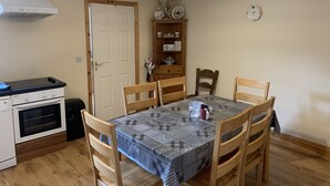 A compact kitchen with a stove, oven, and a dining area with a table and chairs. - Townhome Manorhamilton (Manorhamilton)