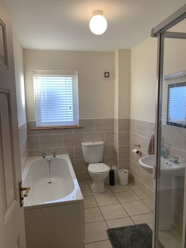 A bathroom with a bathtub, toilet, sink, and a window with blinds. - Townhome Manorhamilton (Manorhamilton)