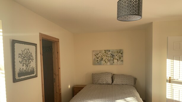 A bedroom with a bed, a door, a window, and a wall with a picture. - Townhome Manorhamilton (Manorhamilton)
