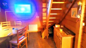 A wooden interior with a dining area, a staircase, and a kitchen.