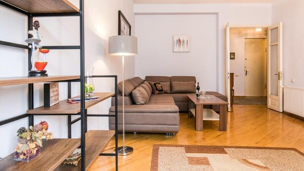 Moderni olohuone, jossa on kulmasohva, sohvapöytä ja kirjahylly.