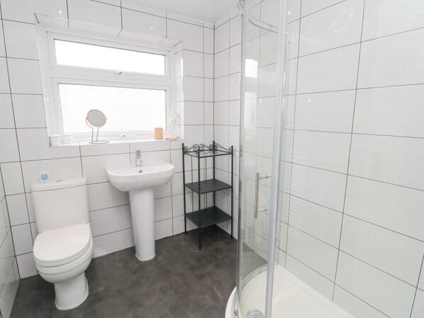 Une salle de bain équipée de toilettes, d’un lavabo et d’une douche à parois de verre.
