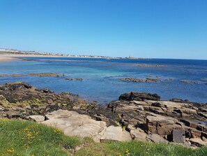 Un paysage côtier caractérisé par un terrain rocheux et une vue dégagée sur la mer.