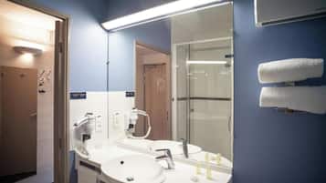 Une salle de bain d’hôtel avec deux lavabos, un miroir et une douche.