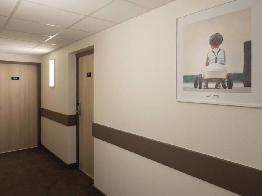 A hotel hallway with doors, a framed picture on the wall, and a carpeted floor.