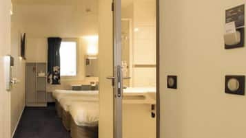 Een hotelkamer met een bed, een bureau, een stoel, een raam en een badkamer.