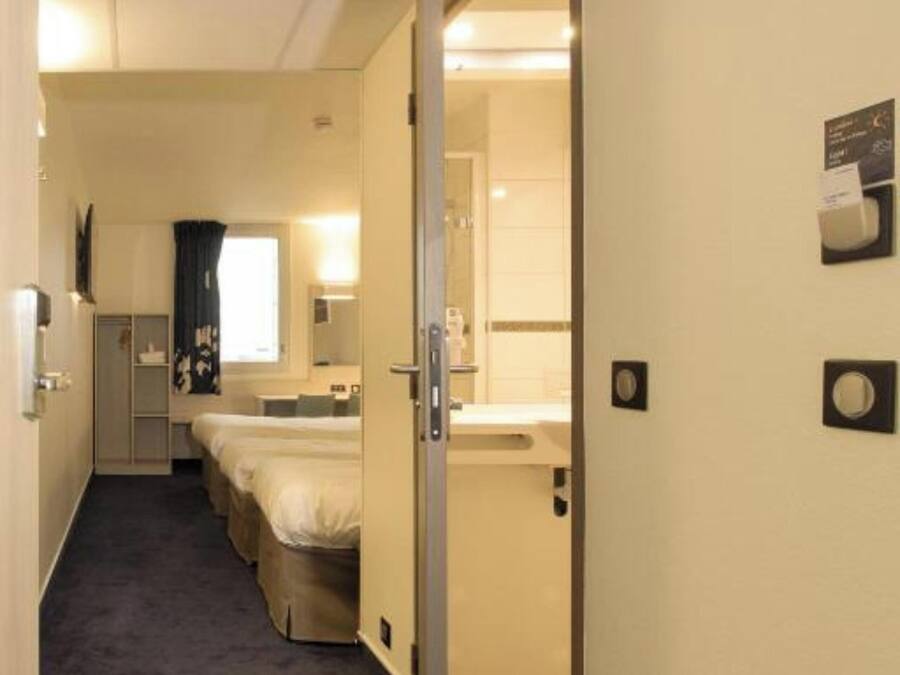 Een hotelkamer met een bed, een bureau, een stoel, een raam en een badkamer.