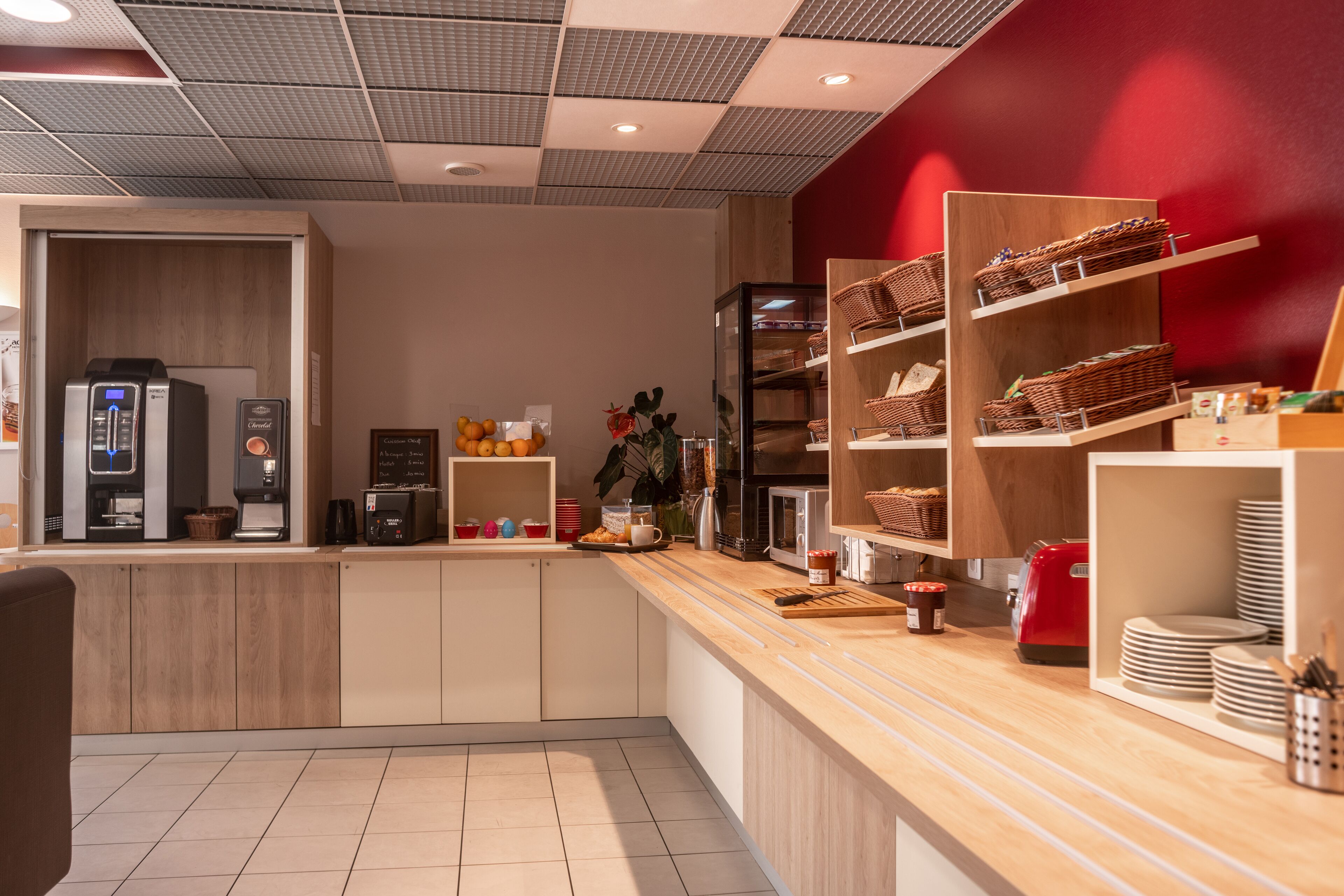 Een moderne keuken met inbouwapparatuur, houten kastjes en een rode accentmuur.
