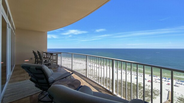 A balcony with a view of the beach and ocean. There are two chairs and a small table. - New Complex!  Lazy River/Slide, 2BR Beachfront! (Orange Beach)