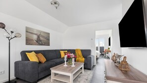 Una sala de estar moderna con un sofá gris, una mesa de centro de madera y un cuadro en la pared.