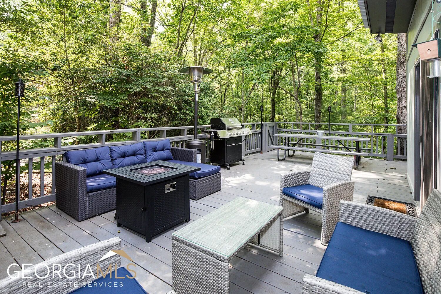 A deck with outdoor furniture, a grill, and a pergola.