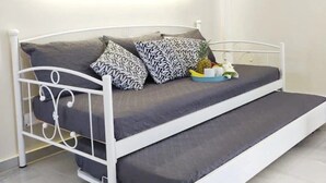 Ein modernes Bett mit Metallgestell, grauer Bettwäsche und gemusterten Kissen.