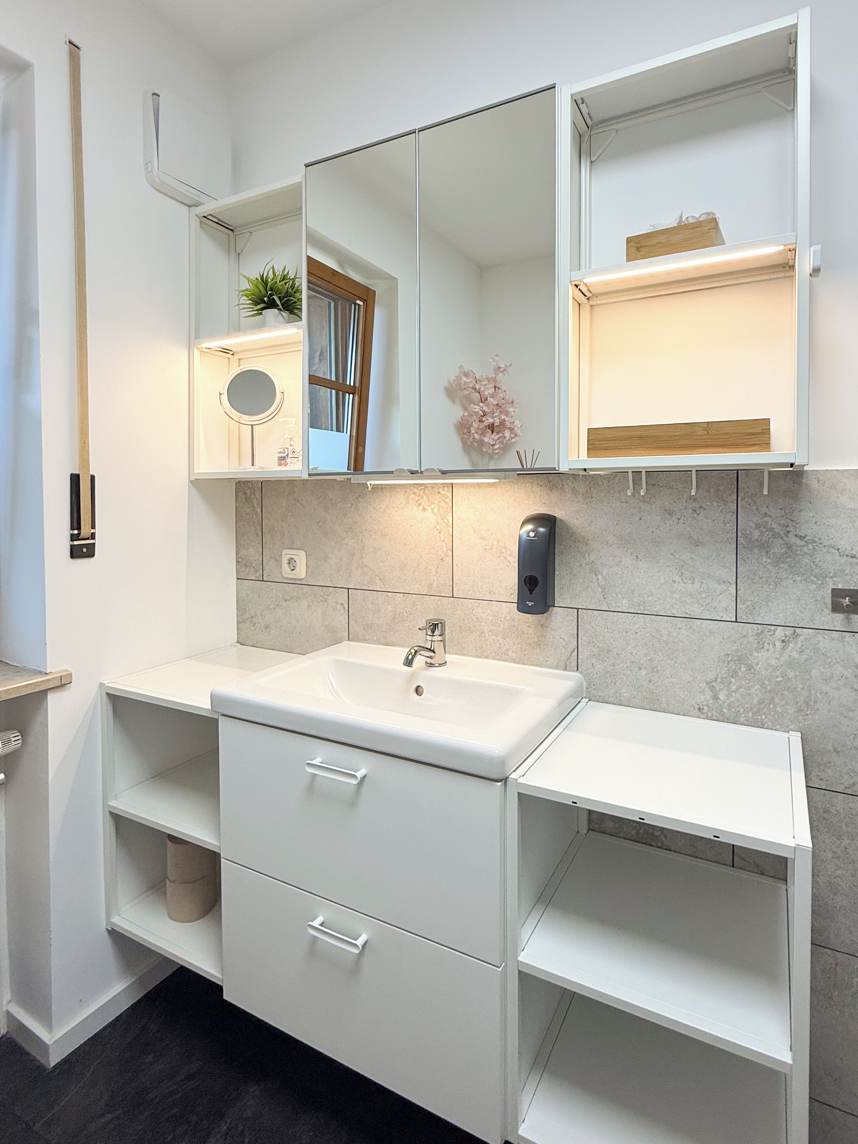 A modern bathroom with a white vanity, a large mirror, and a marble backsplash.