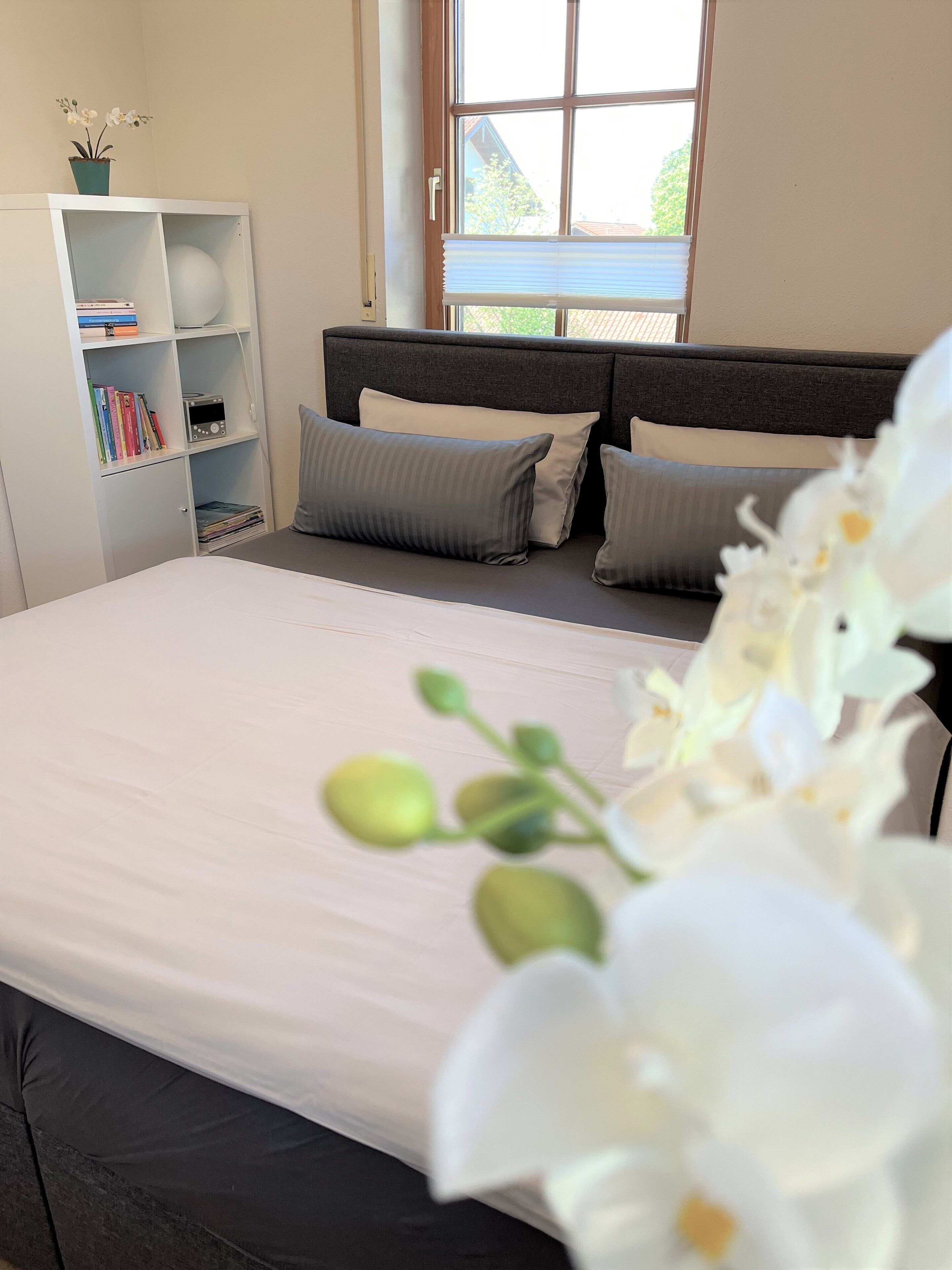 A bedroom with a bed, a bookshelf, and a window.