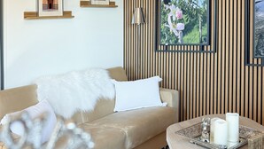 A modern living room with a beige sofa, a round coffee table with candles, and framed pictures on the wall. - Apartment Wohlfühlplatzl - Urgemütlich & Ruhig (Vogtareuth)