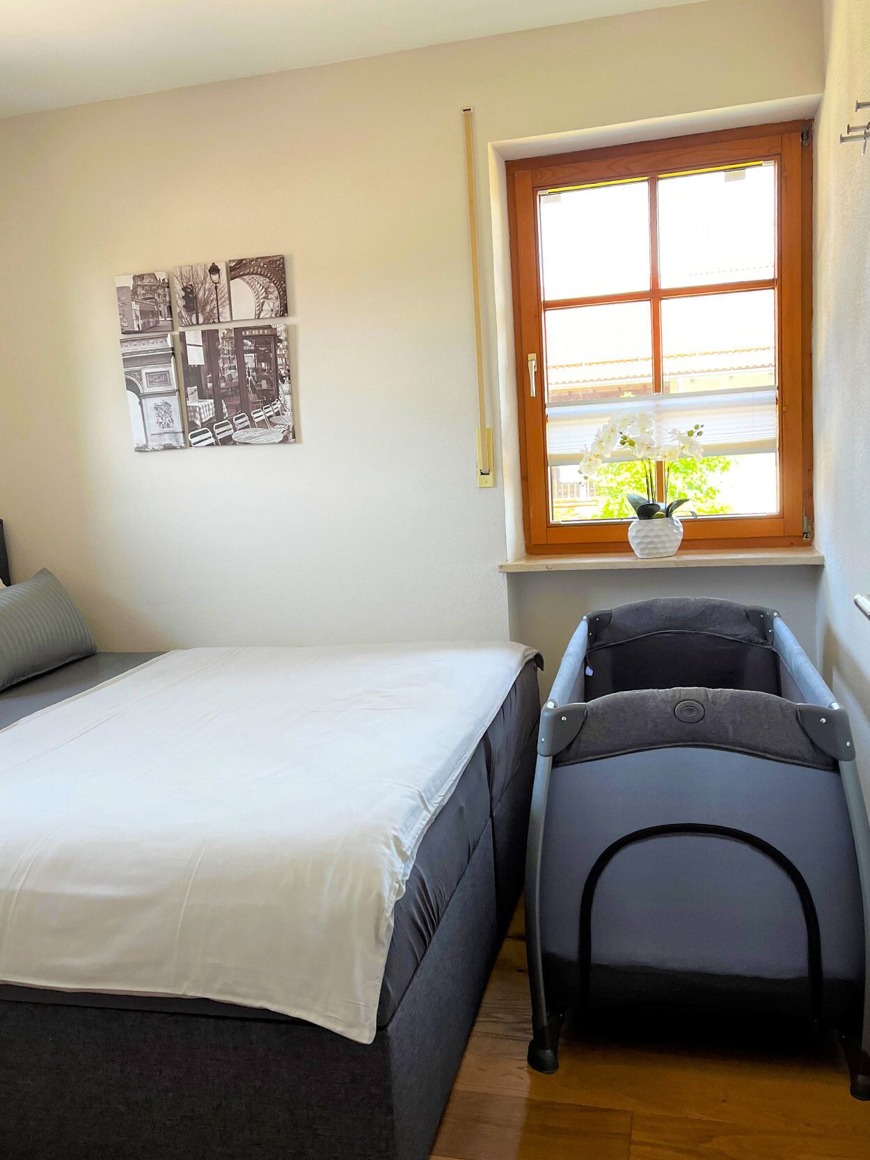 A bedroom with a bed, a window with a view, and a stroller.