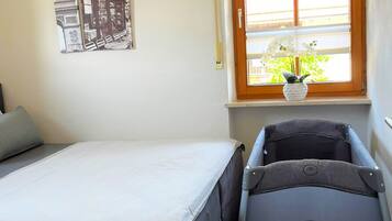 A bedroom with a bed, a window with a view, and a stroller.