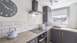 A modern kitchen with a large wall clock, a toaster, and a kettle on the counter. - Host & Stay | The Nest (Whitby)