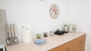 Eine Küche mit Uhr, Kochgeschirr, Gläsern, einer Kaffeemaschine und einem Wasserkocher.