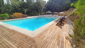 A rectangular swimming pool with a wooden deck surrounding it.