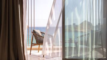 Un balcón con una silla de mimbre y vista al mar.