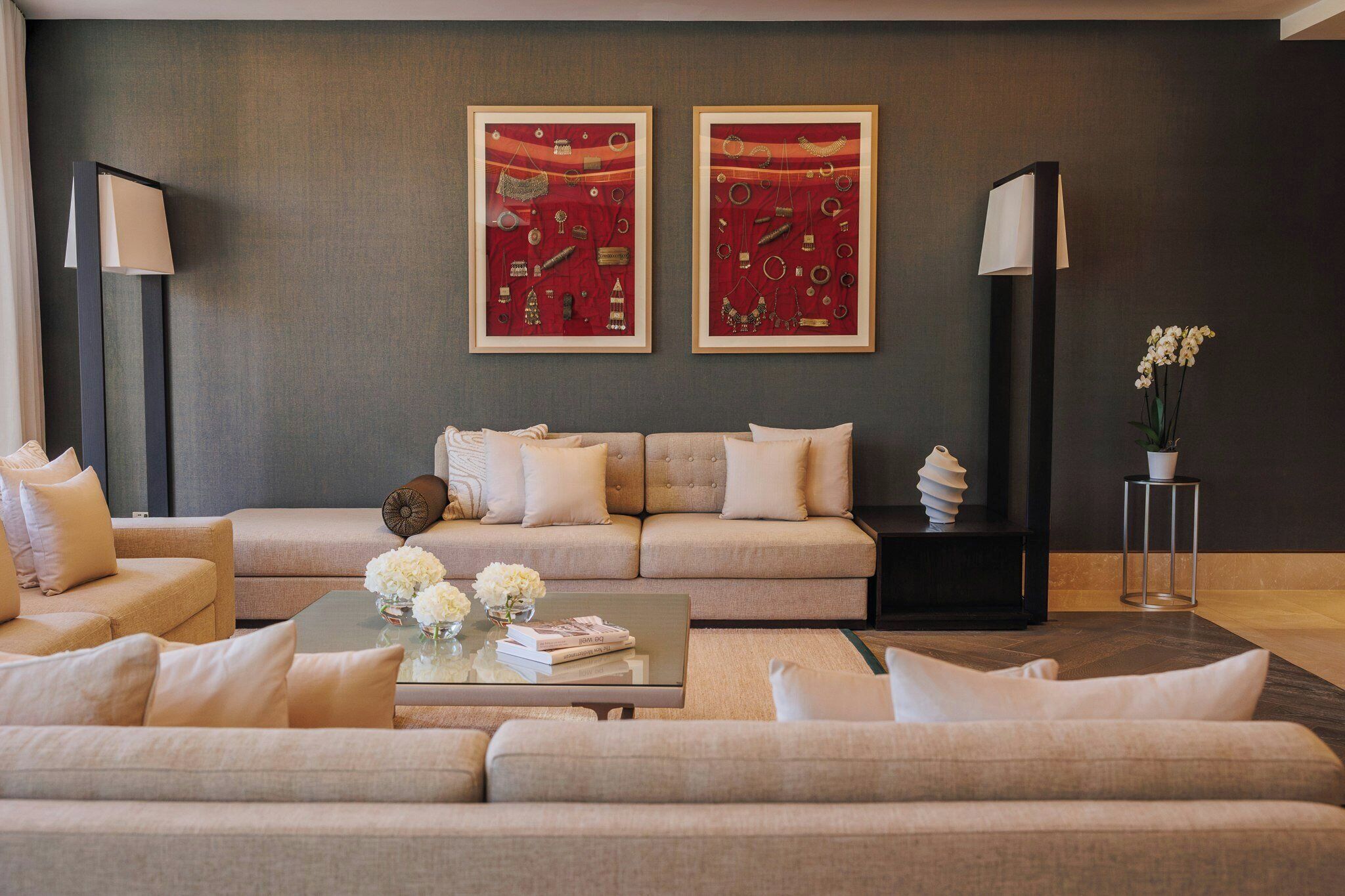 A modern living room with a sofa set, a coffee table with flowers, and two framed artworks on the wall.