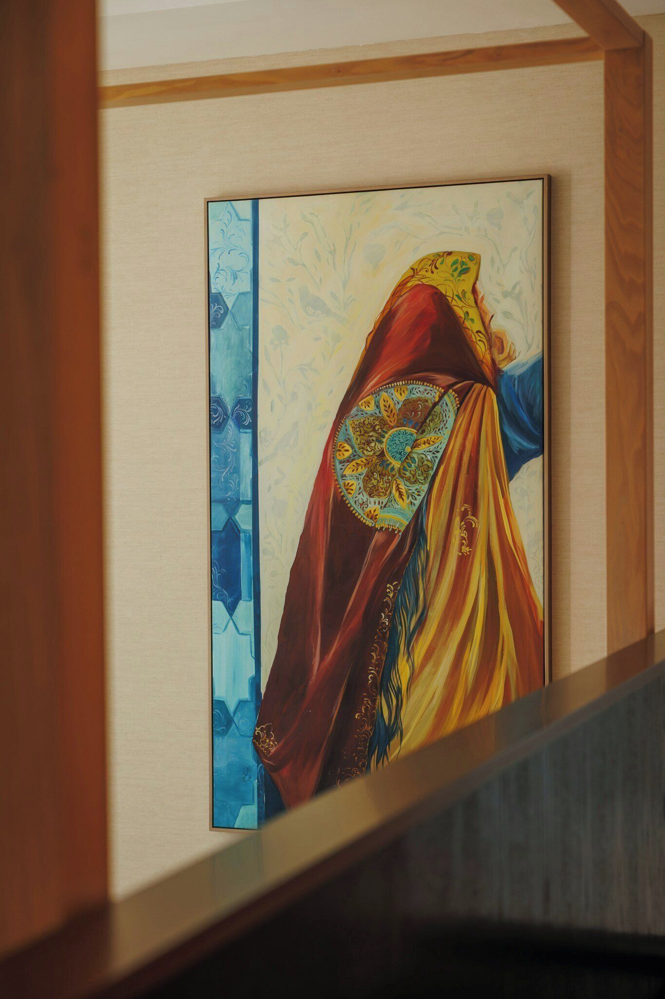 Une œuvre d’art encadrée, ornée d’un motif décoratif, qui pourrait être une tapisserie ou un textile, et qui est exposée sur un mur.