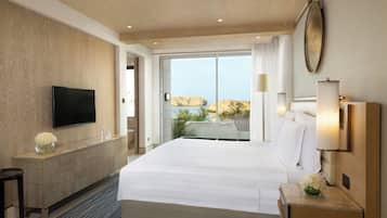 Ein Hotelzimmer mit einem großen Bett, einem Flachbildfernseher, einem Holzkabinett und Blick ins Freie.