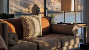 A modern living room with a sofa, a lamp, and a view of a mountainous landscape through large windows.