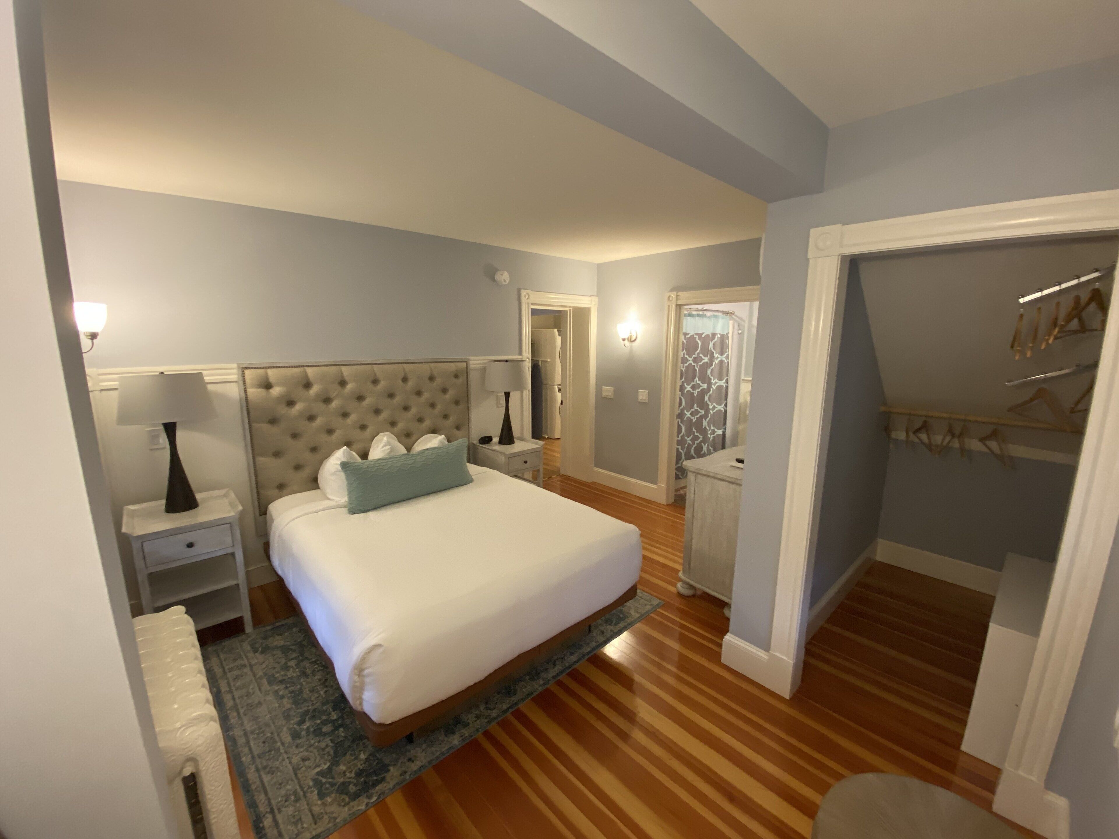 Een slaapkamer met een groot bed, twee nachtkastjes, een kaptafel, een garderobe en een badkamer met douche en toilet.