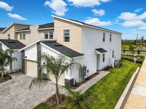 A modern residential building with a flat roof, multiple windows, and a well-maintained lawn.