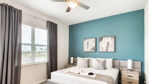 Ein Schlafzimmer mit einem Bett, zwei Nachttischen, einem Deckenventilator und einem Fenster mit Vorhängen.