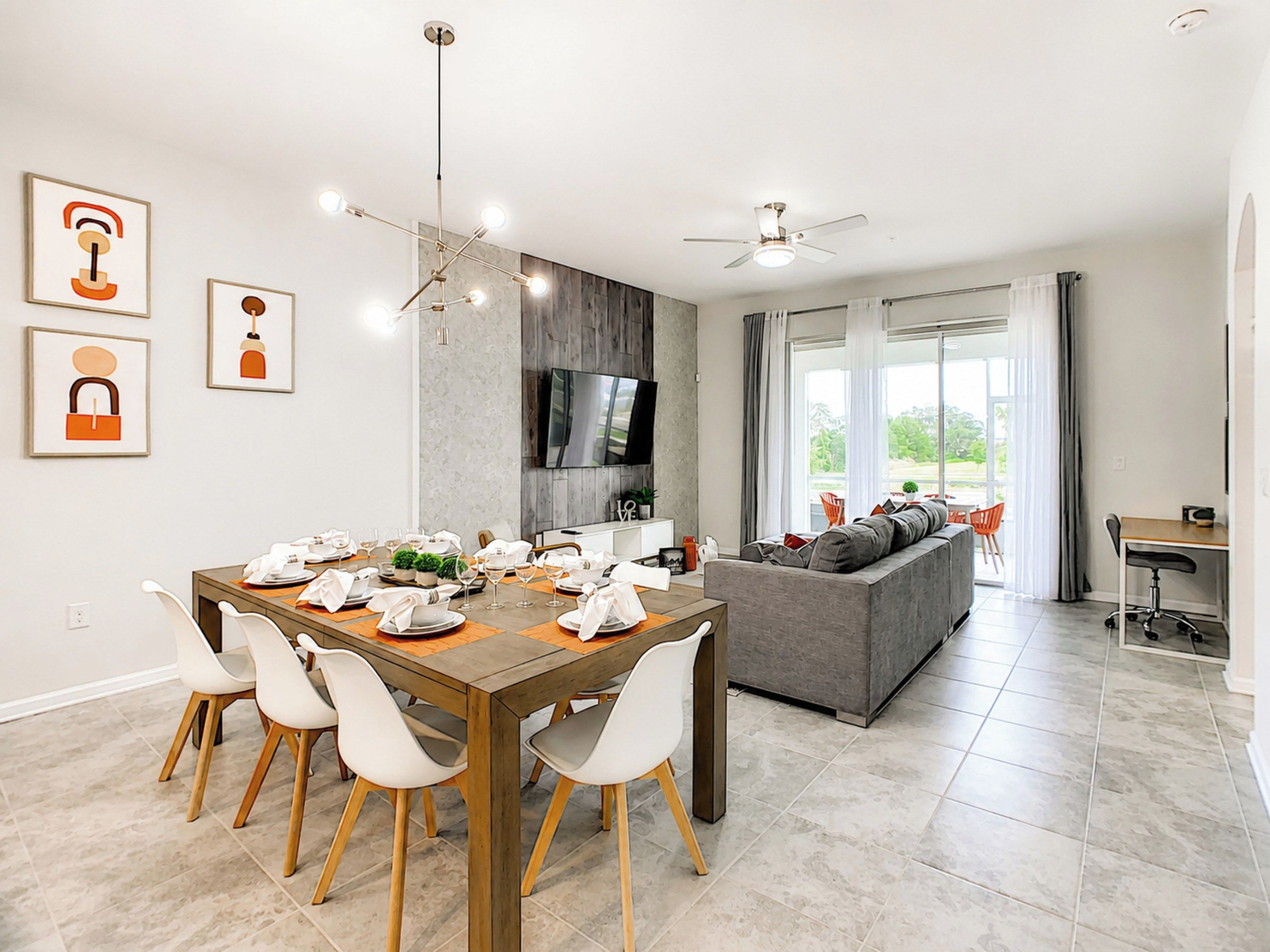 Un espace repas moderne avec une table en bois, des chaises blanches et un ventilateur de plafond.