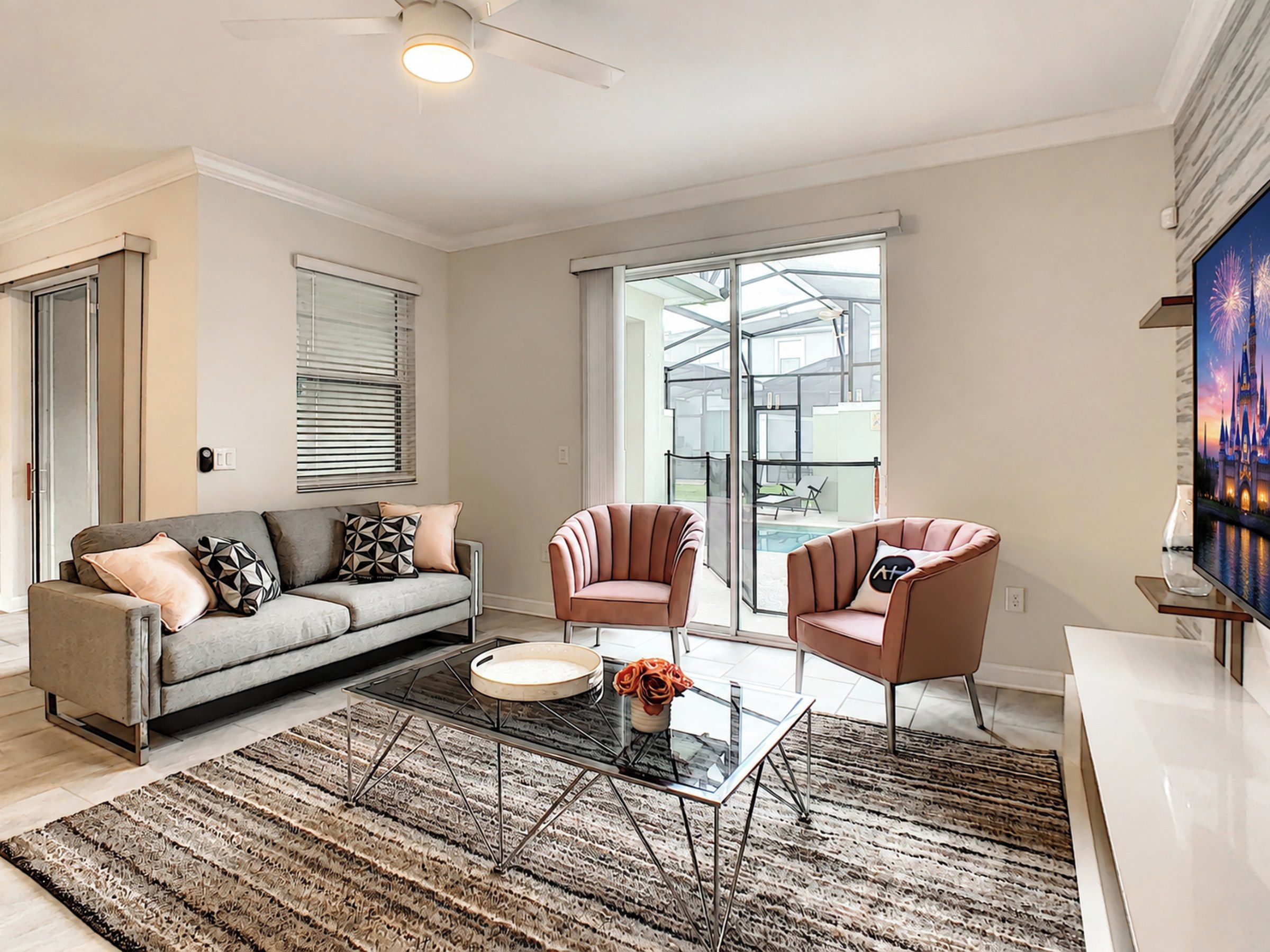 A modern living room with a sofa, two armchairs, a glass coffee table, and a large window overlooking a pool.
