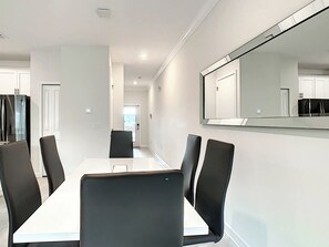 A conference room with a long table and six chairs, a large mirror on the wall, and a door leading to another room.