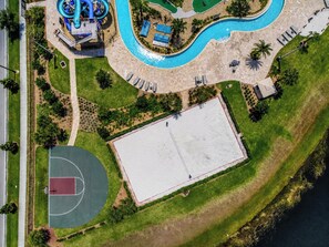 An aerial view of a resort with a swimming pool, a basketball court, and a large open area.