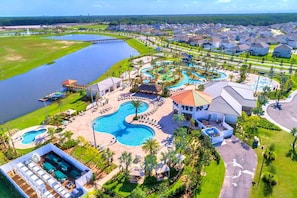 Un resort con varias piscinas, una gran extensión de agua y edificios residenciales.