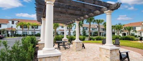 A covered patio area with stone columns, picnic tables, and outdoor seating.