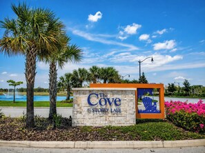 A sign for 'The Cove at Stoney Lake' with a view of a lake and palm trees.