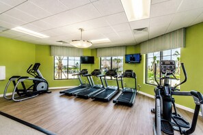 A fitness center with treadmills, an elliptical, and a television screen.